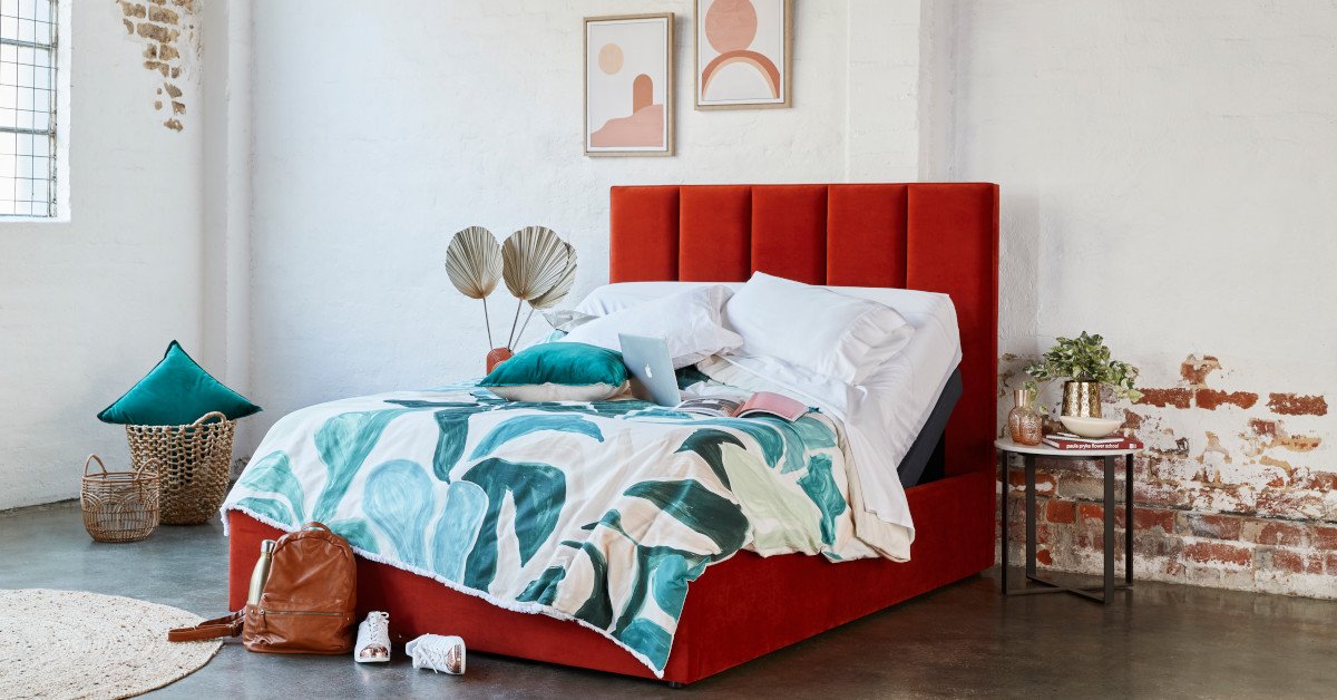 Bright red bed frame with green bedspread and accents in industrial-style bedroom