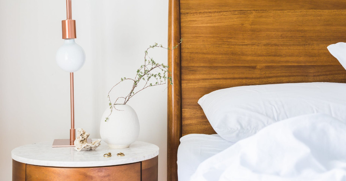 Brown wooden headboard and nightstand with rose gold lamp and small vase