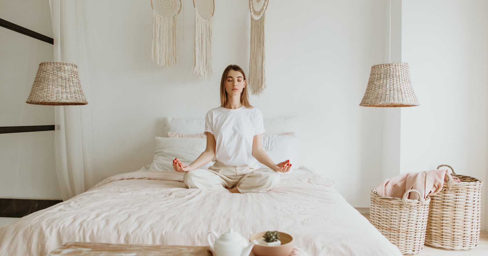 woman meditating on bed in white bedroom