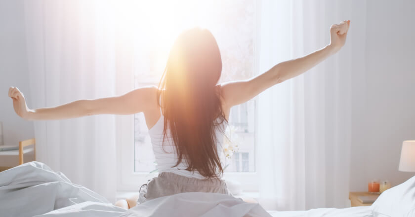 A person waking up happily in bed