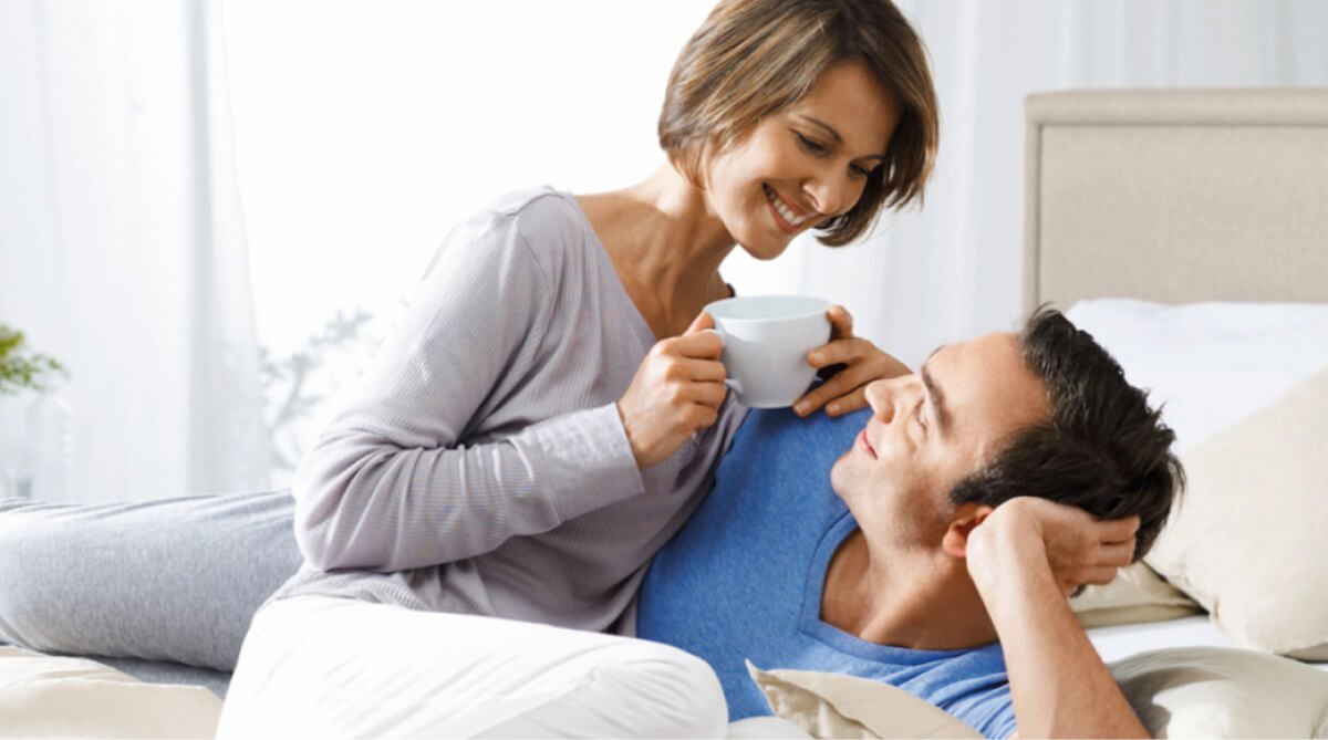 A couple enjoying coffee together in bed