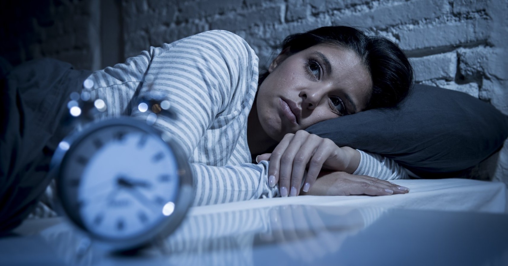 Women awake next to an alarm clock