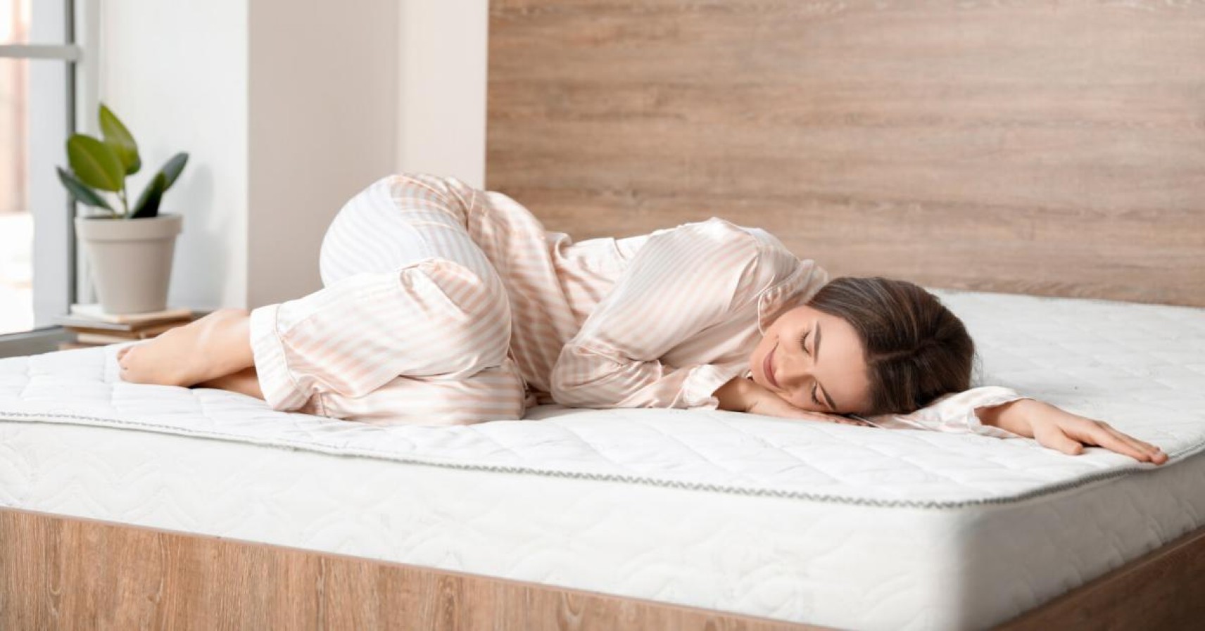 Woman in matching pajama set happy on mattress